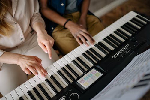 Close-Up Shot of Two People Playing Piano
