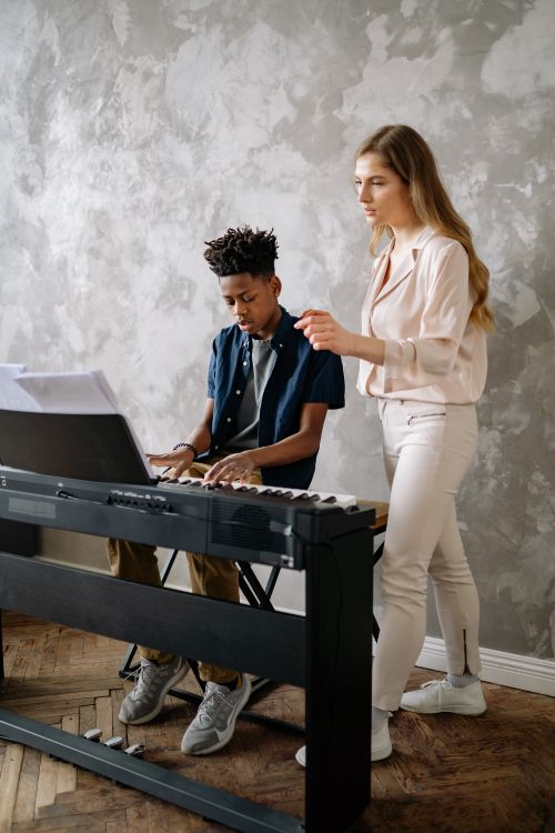 Free A young boy and female instructor learning and teaching piano indoors. Stock Photo
