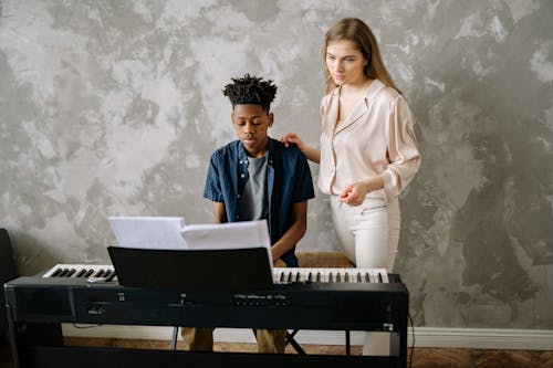 Woman Standing Beside a Boy Playing Piano