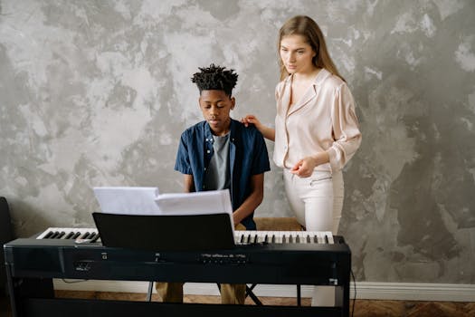 A boy learns piano from a teacher in a home setting.