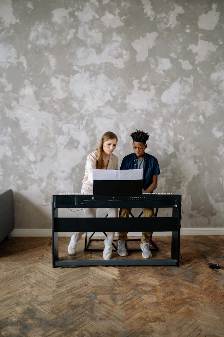 Woman Teaching A Young Boy How To Play A Piano