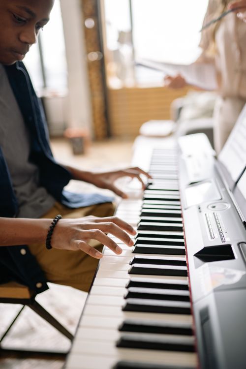 Free Close-up of a boy playing an electronic keyboard indoors, focusing on hands and keys. Stock Photo