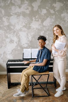 A young musician practices piano with an instructor in a bright indoor setting.