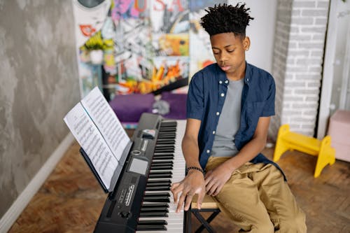 Boy Sitting on a Chair next to a Music Keyboard