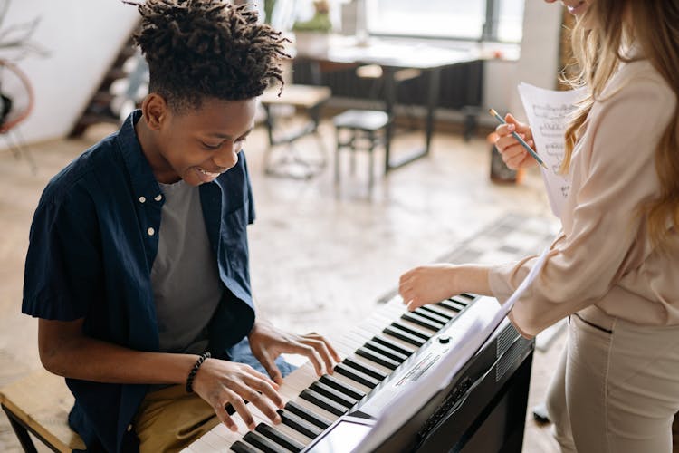 Teacher Teaching Piano To A Boy