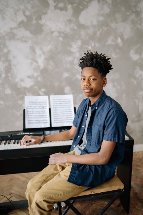 Free A young musician seated at a piano with sheet music, exuding talent and expression. Stock Photo