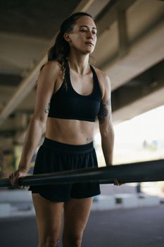 Fit woman in active wear working out on metal bars at an outdoor gym.