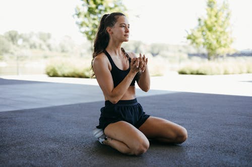 A Woman Doing Stretching while Kneeling