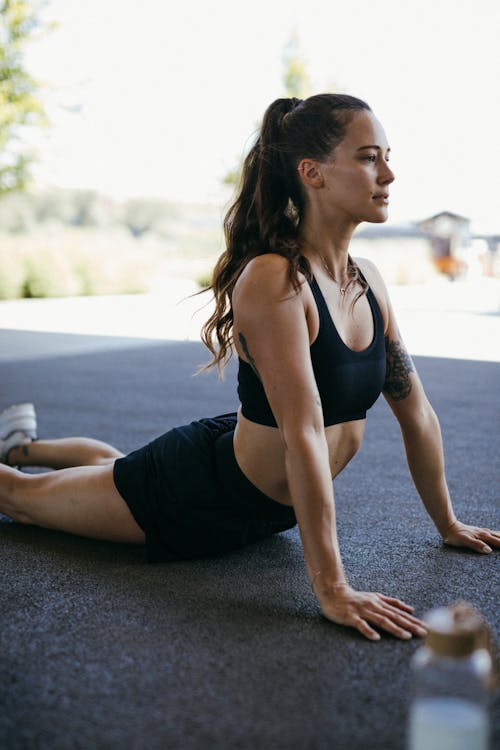 A woman in a black sports bra and shorts squatting on a white floor photo –  Stretching Image on Unsplash