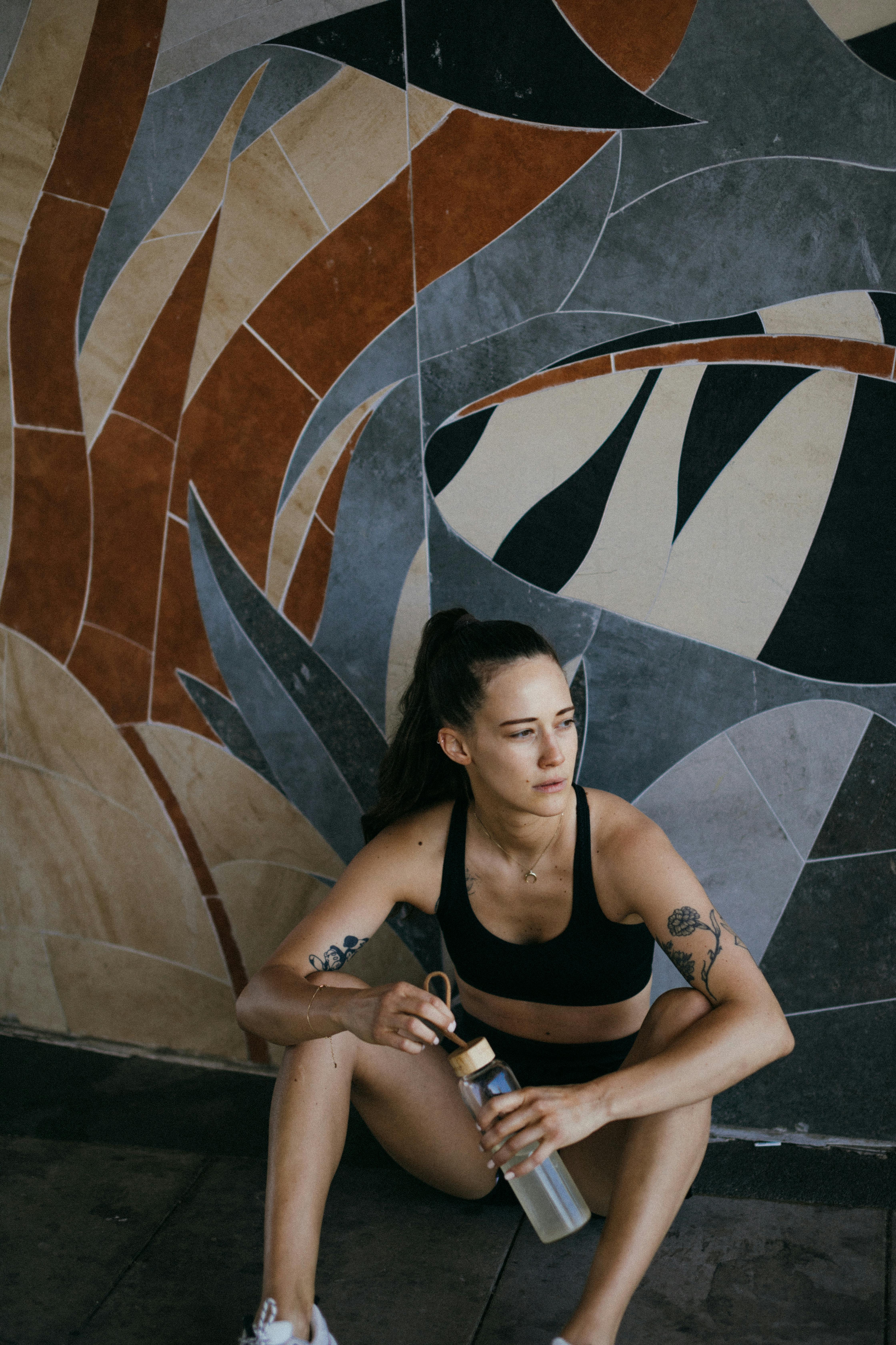 Woman in black sports bra and black shorts sitting on concrete