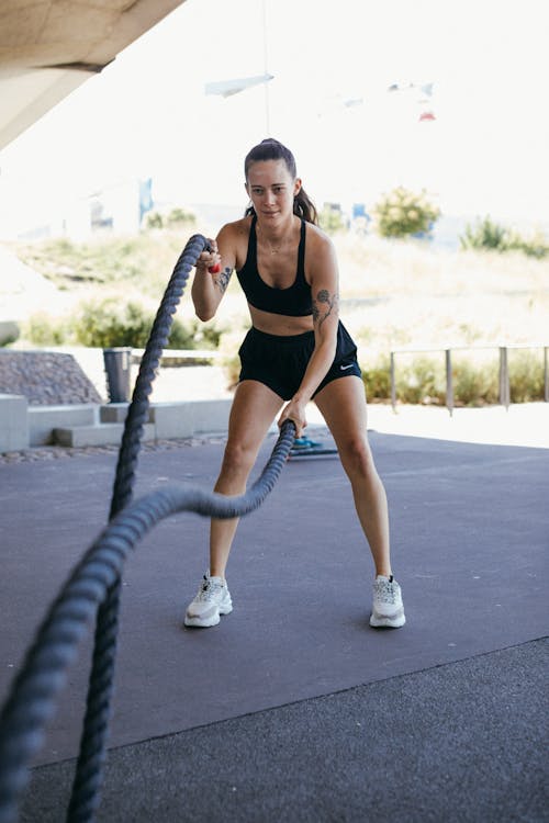 Woman in Black Sports Bra and Black Shorts Holding Ropes