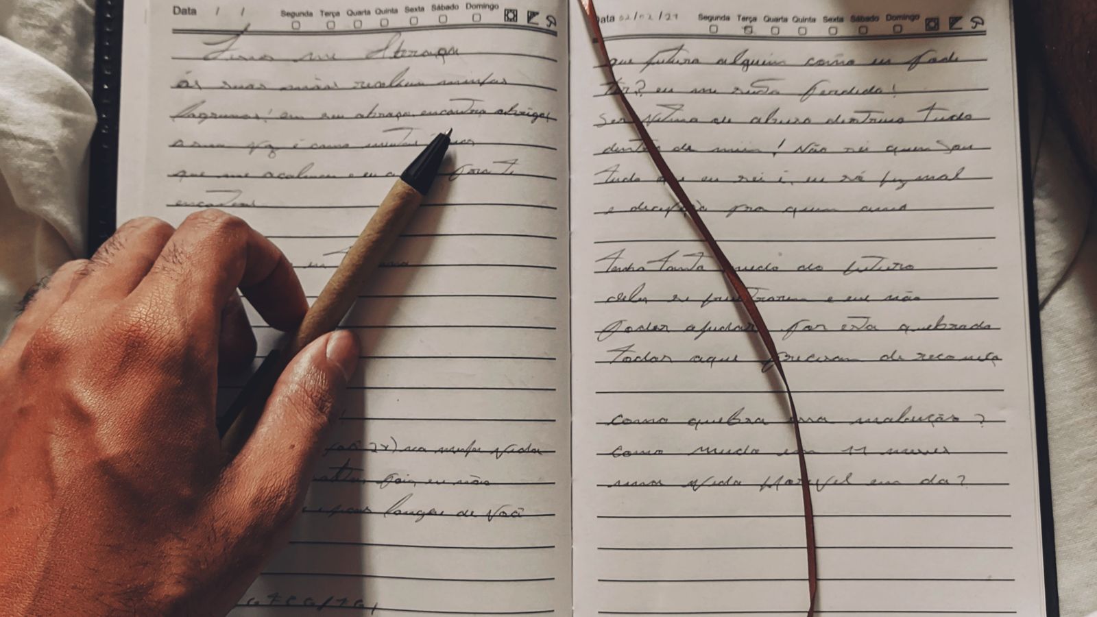 A person writing in an open notebook with a pen