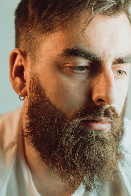 Free Vertical close-up portrait of a bearded man with thoughtful expression and facial hair details. Stock Photo