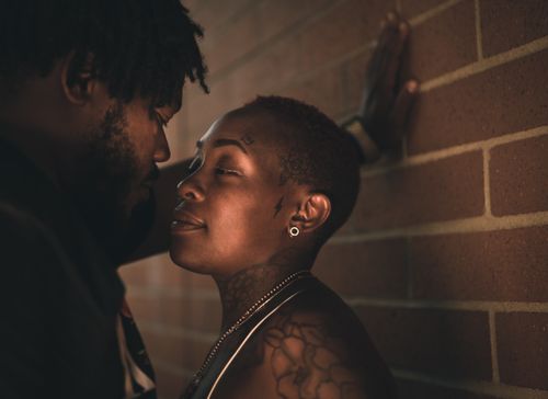 Free A close-up of a couple sharing an intimate moment against a brick wall. Stock Photo