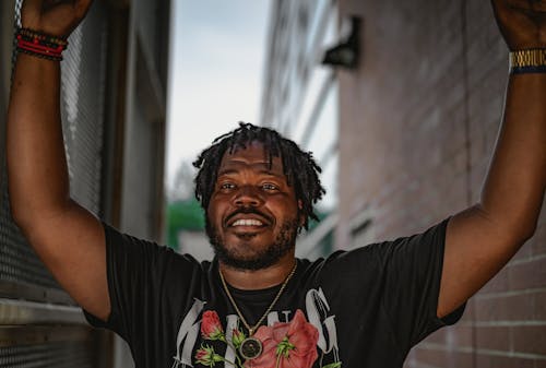 Man wearing Black T-shirt with Hands Raised