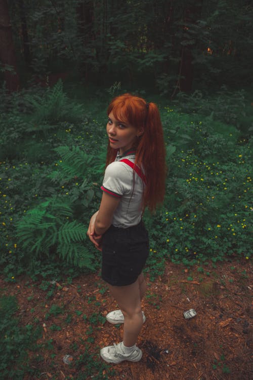 Woman in White Polo Shirt and Black Shorts Standing Near Plants