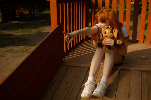 Woman in a Playground Holding a Stuffed Toy