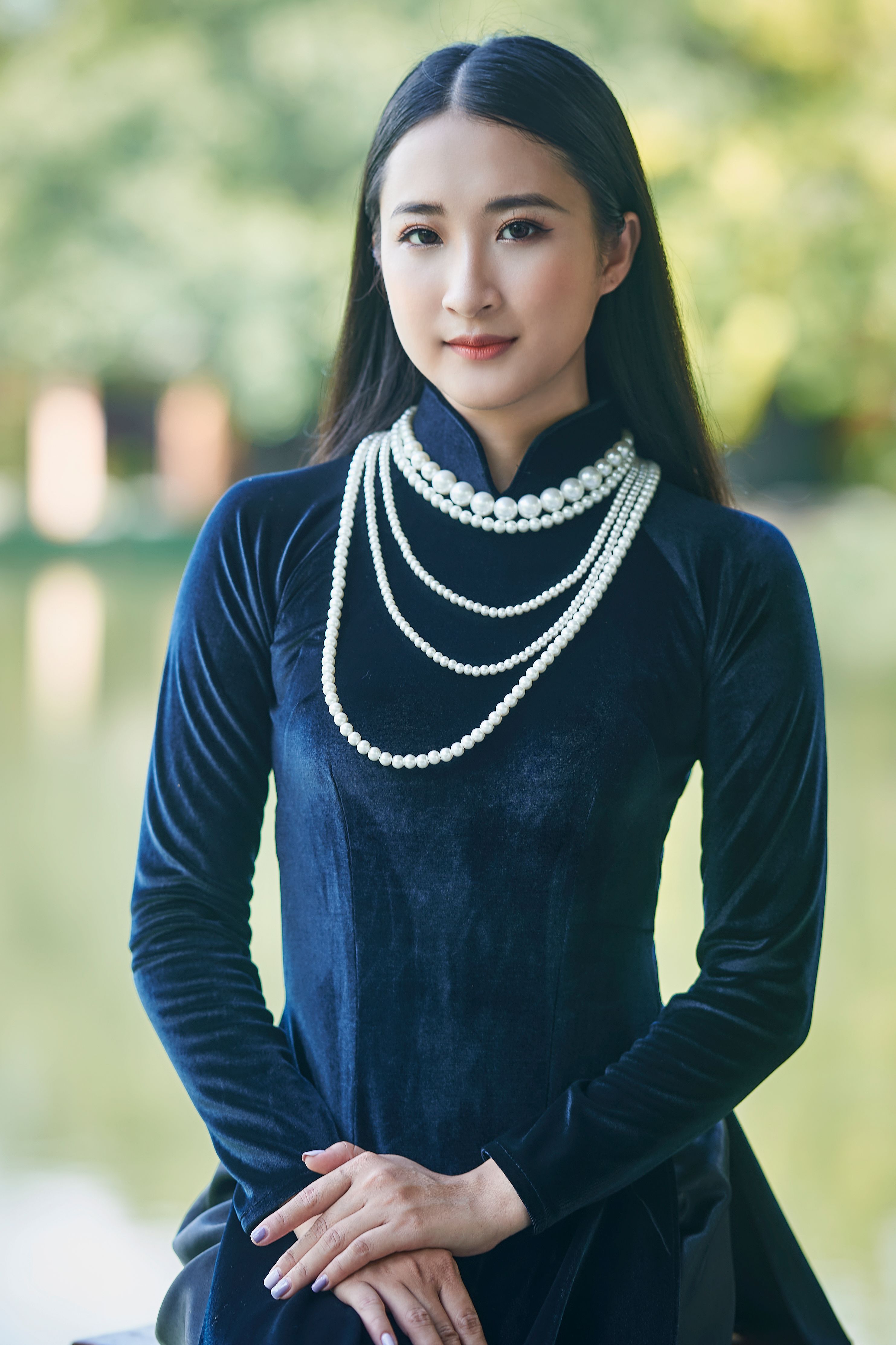 Portrait of a beautiful woman wearing pearls and a traditional dress outdoors.