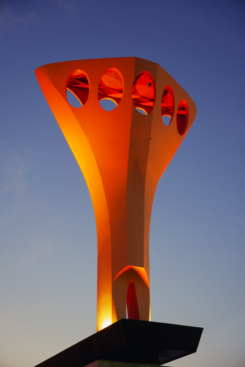 Free A modern, illuminated structure with circular cutouts set against a twilight sky. Stock Photo