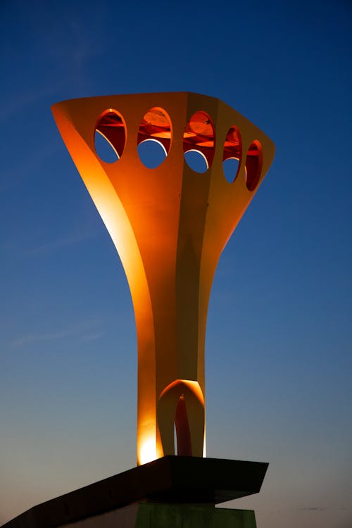 Orange Metal Sculpture on Architecture against Blue Sky