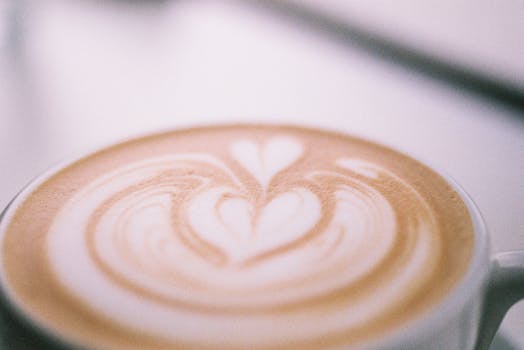 Close-up shot of heart shaped latte art in a steaming coffee cup, perfect for beverage enthusiasts.