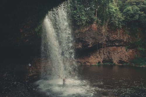 A Man Standing Under a Waterfall