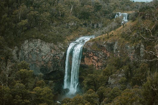 A stunning aerial view of cascading waterfalls in a vibrant forest setting, showcasing the beauty of nature.