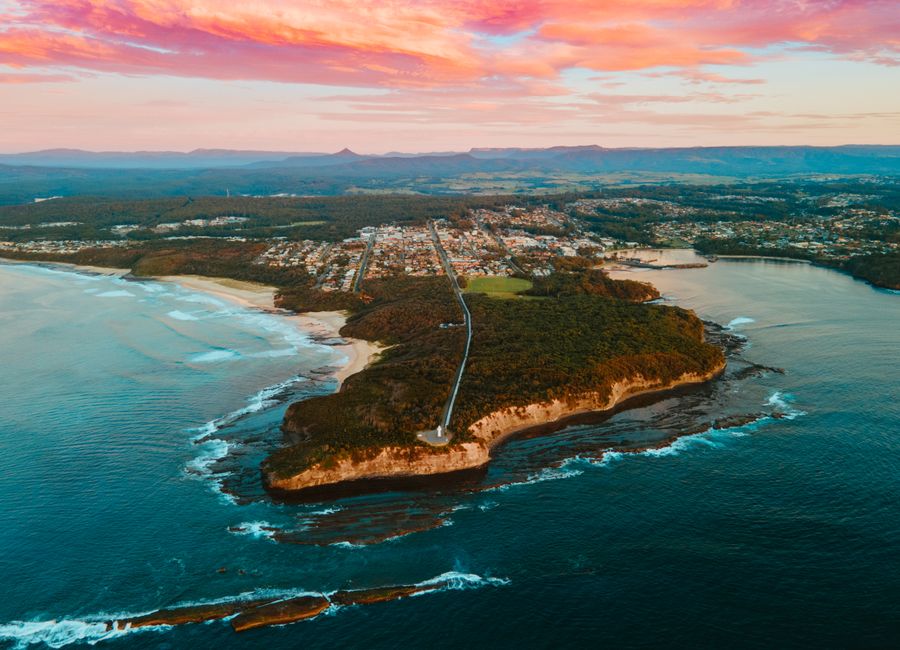 Stunning aerial shot of Ulladulla, NSW coast at sunset showcasing town, forest, and ocean scenery.