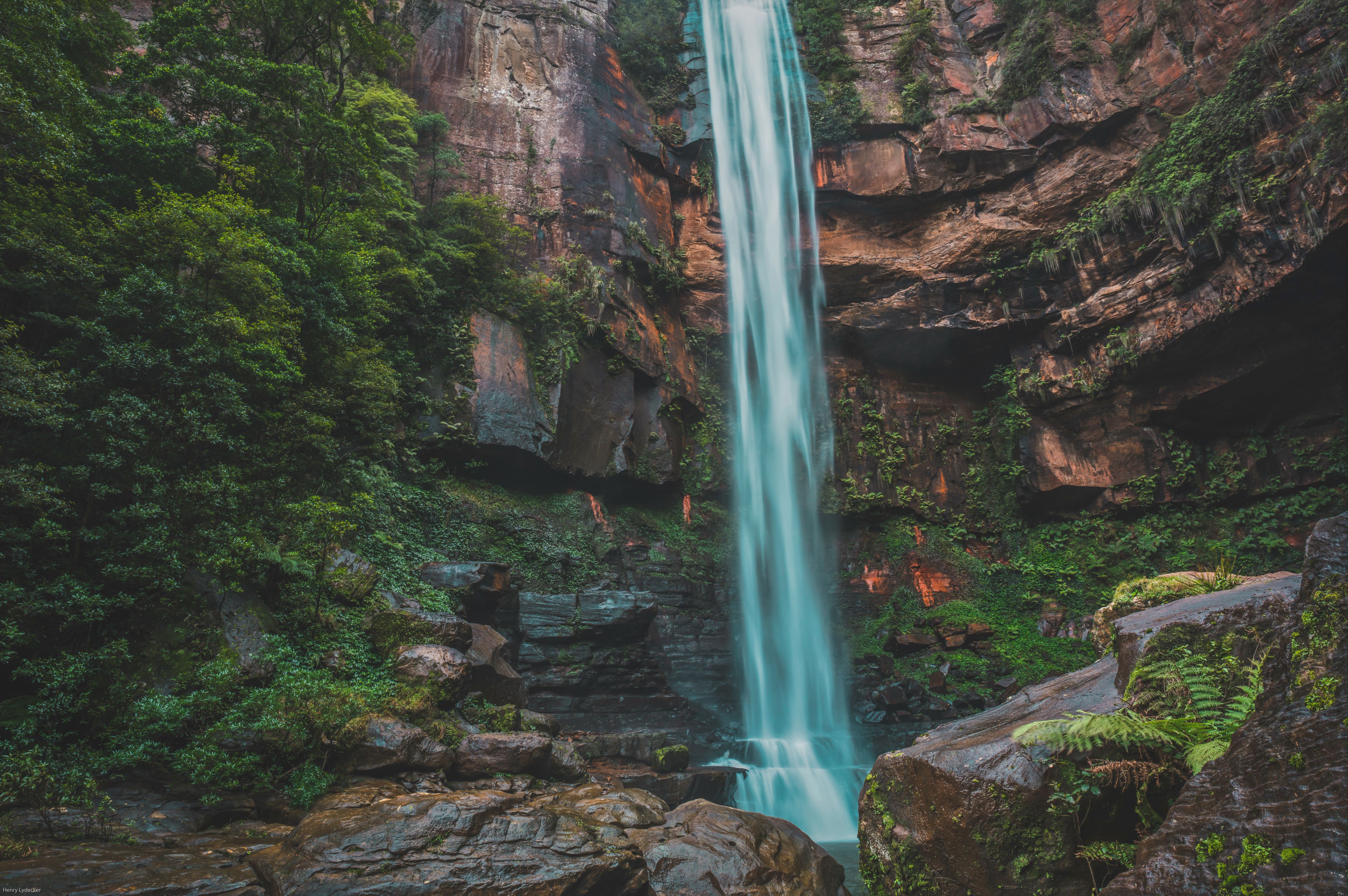 A breathtaking waterfall cascading down a rocky cliff surrounded by lush green vegetation.