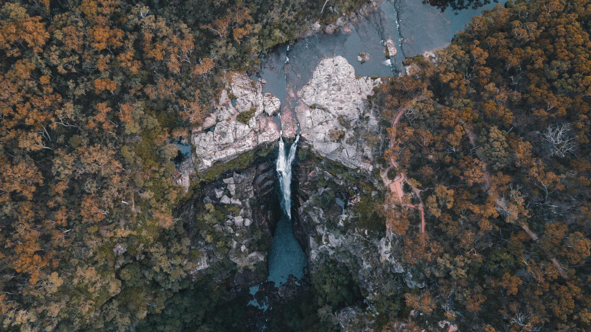 Breathtaking aerial view of Carrington Falls surrounded by lush forest in NSW, Australia.