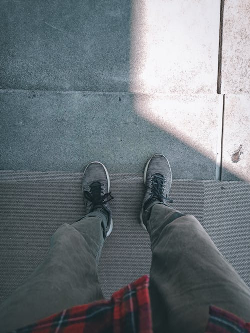 Free Person in Gray Pants and Sneakers Standing on Concrete Floor Stock Photo