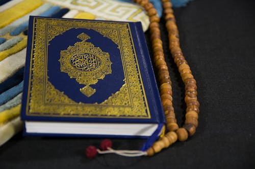 Free Close-Up Shot of a Book beside Prayer Beads Stock Photo