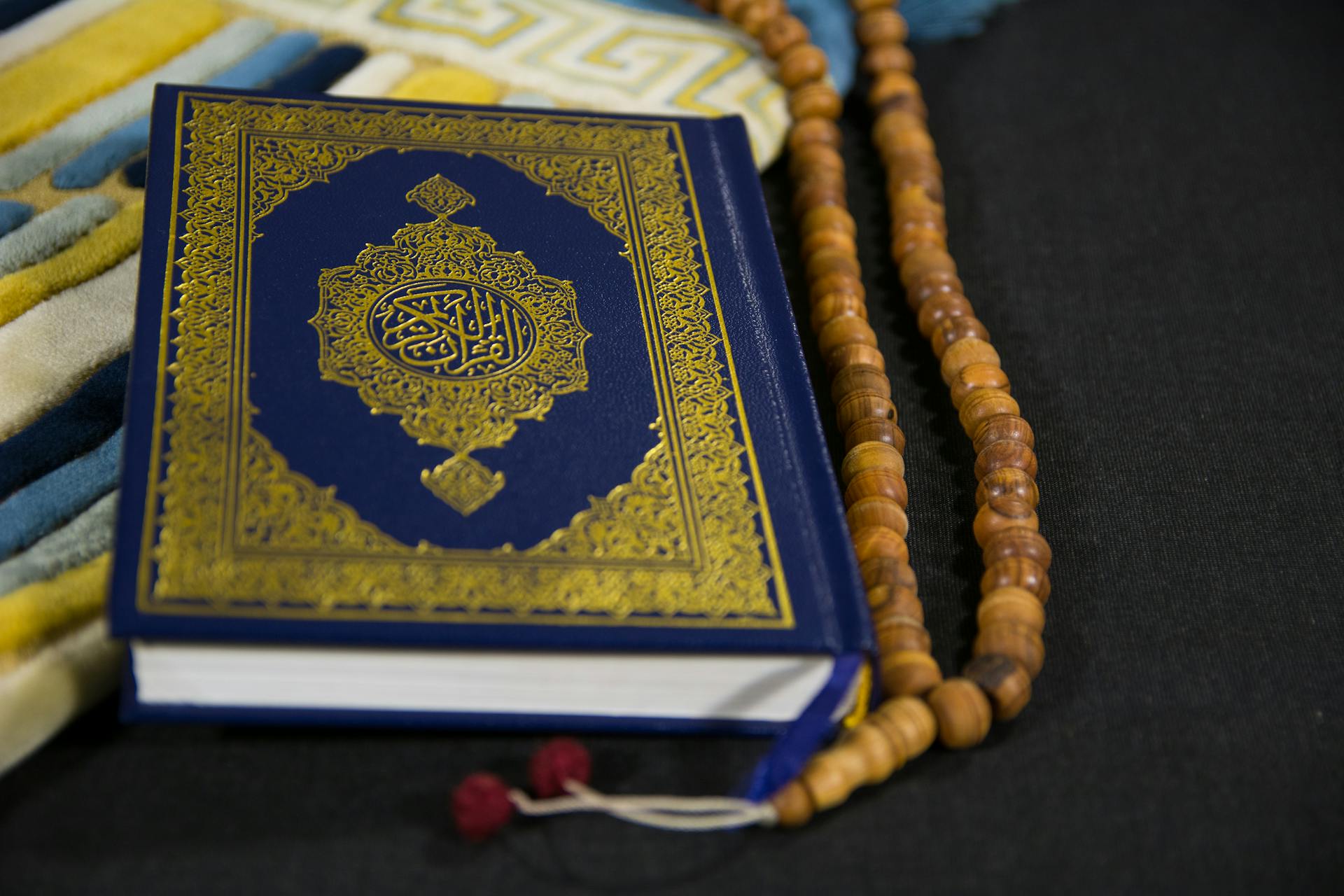 Close-Up Shot of a Book beside Prayer Beads