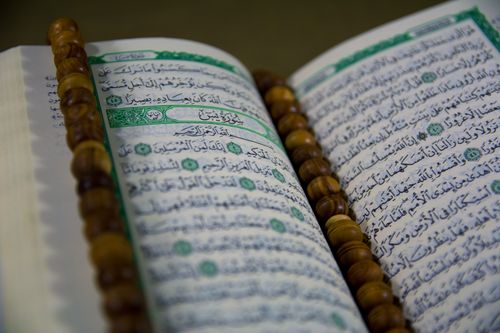 Free Open Quran with prayer beads, showcasing Arabic text and Islamic calligraphy. Stock Photo