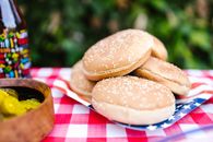 Stack of sesame seed hamburger buns on a checkered tablecloth ready for a summer BBQ.