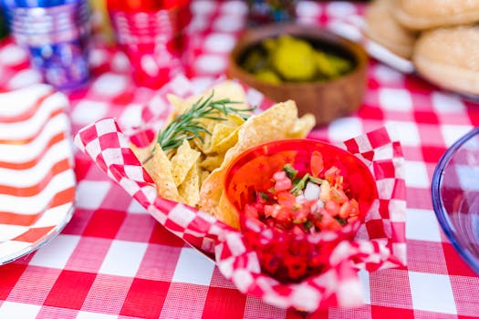 Delicious nachos with salsa served on a vibrant checkered tablecloth setting.
