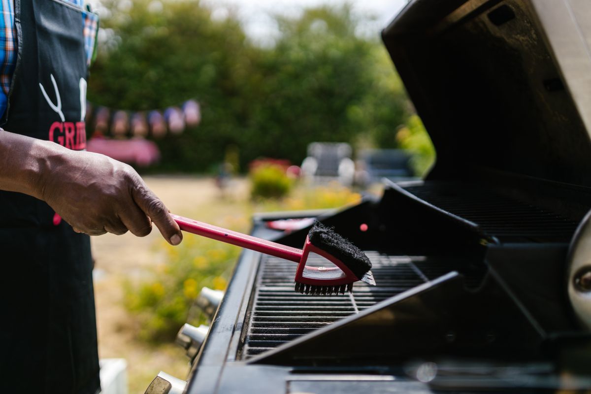 Nettoyage d'une grille de barbecue avec une brosse
