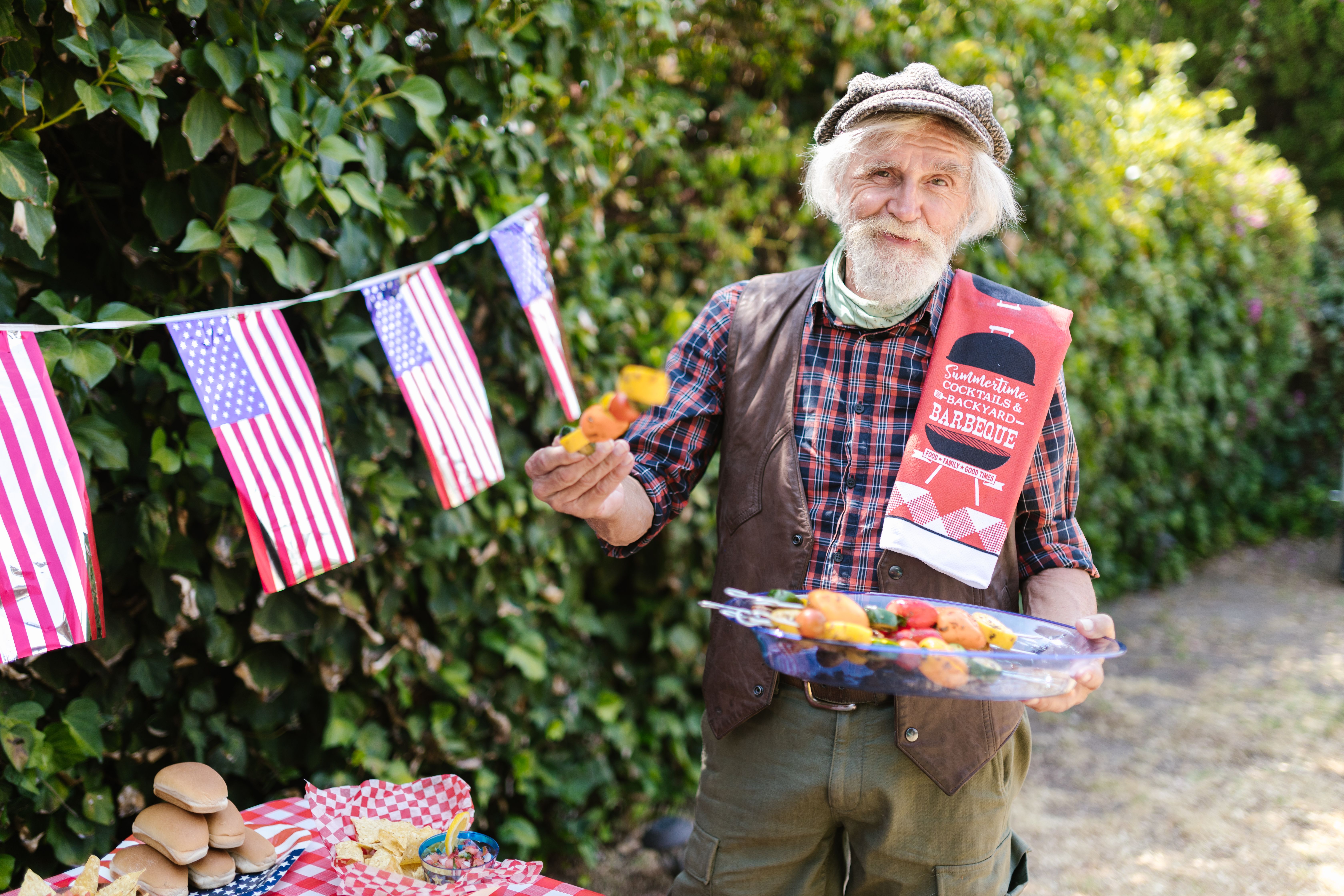 Friends gathered around a backyard grill at an American Fourth of July cookout on a sunny summer afternoon
