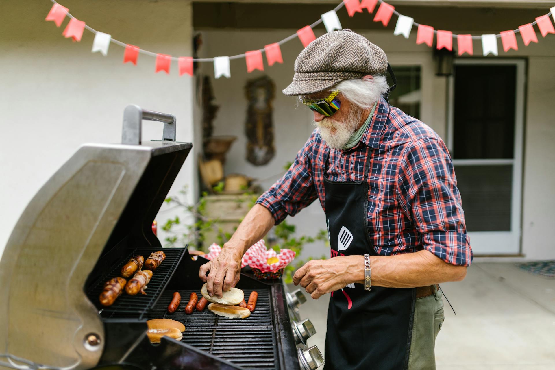 Gråhårig man som grillar korvar