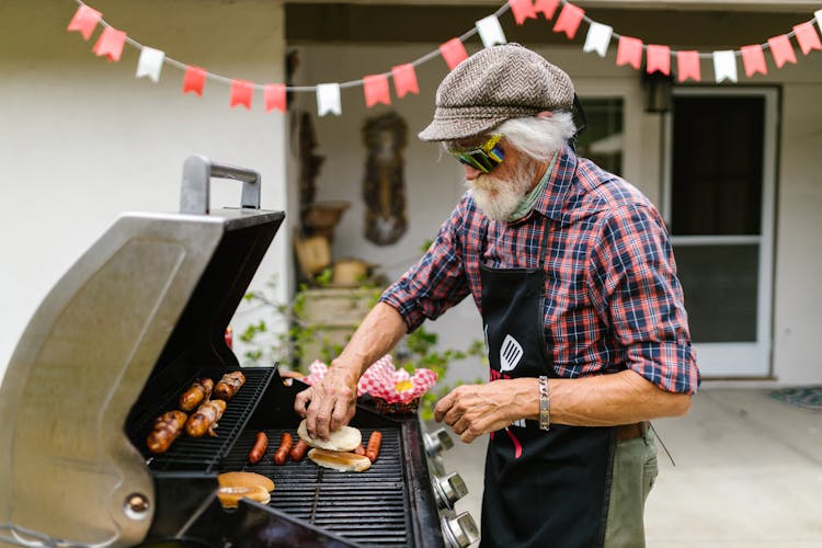 Gray Haired Man Grilling Hot Dogs 