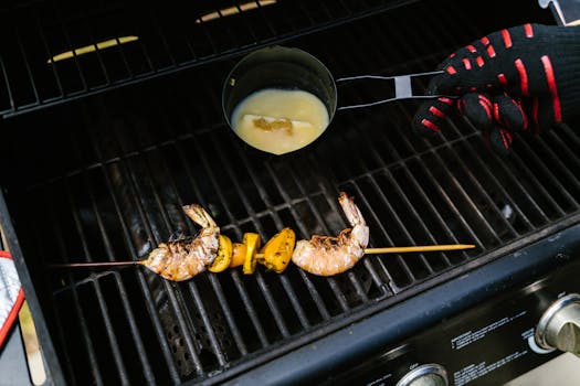 Shrimp skewers with lemon being grilled, seasoned with sauce, on an outdoor barbecue.
