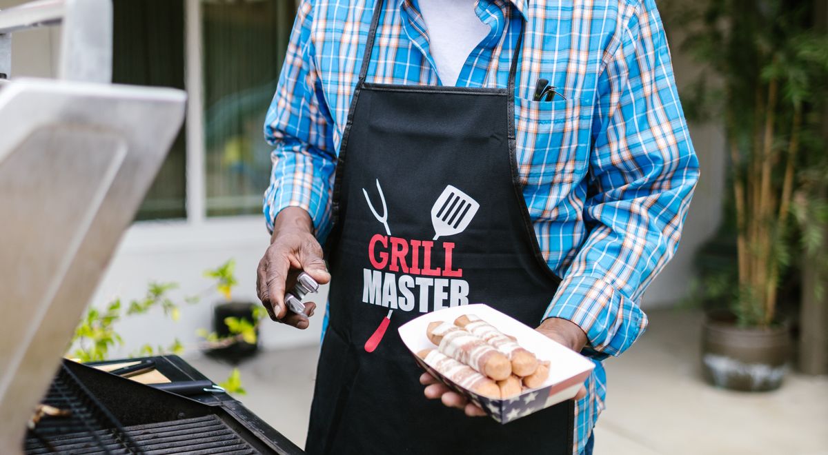 Homme portant un tablier de barbecue devant un grill en extérieur