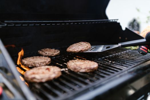 Close-up of beef patties grilling on an outdoor barbecue. Perfect for summer cookouts.