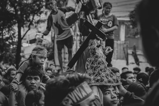 A compelling black and white image of a religious procession featuring a statue and crowd.