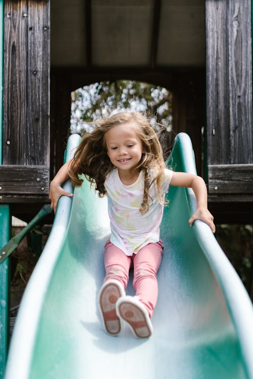 Happy Girl Playing on Slide in the Park