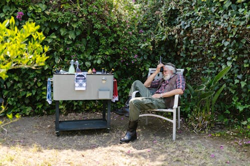 Man Sitting Near the Barbecue Grill in His Backyard