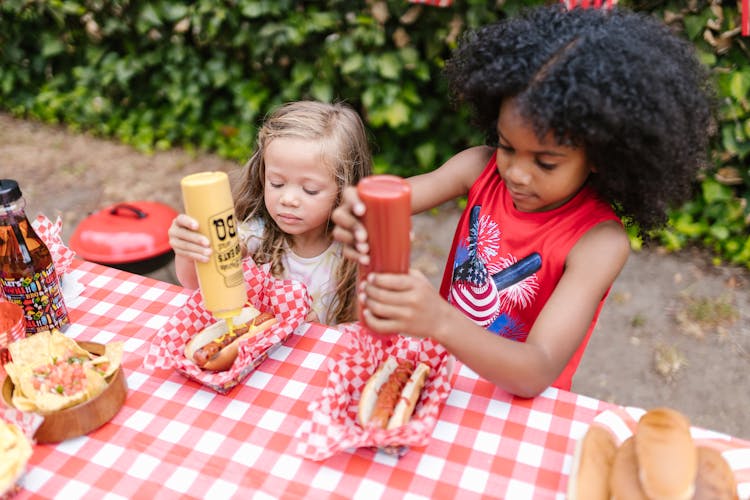 2 Girls Eating Burger And Fries On Table