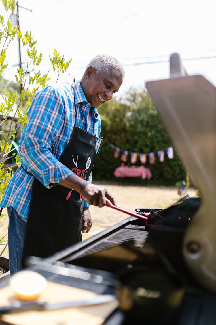 Man Wearing Apron Standing In Front Of Barbecue Grill