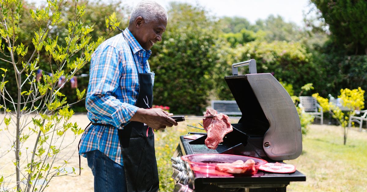 Side View of a Man Cooking Meat in a Griller · Free Stock Photo