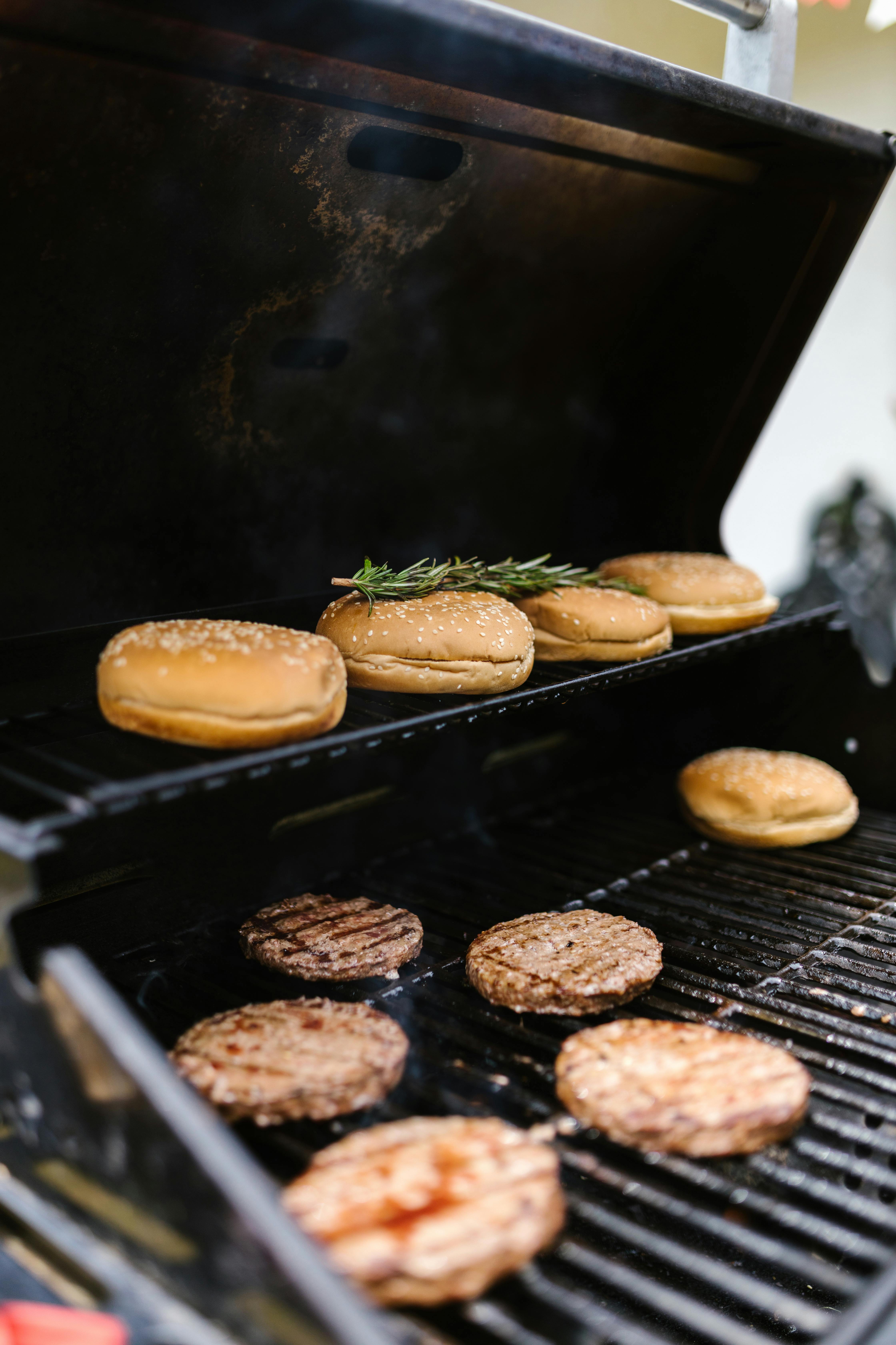 Close-up of burgers and buns grilling, capturing the essence of outdoor cooking.